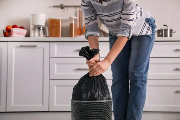 Woman taking garbage bag out of bin 
